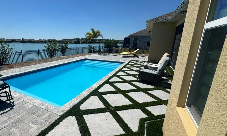 Miami pool with turf and paver deck by a lake