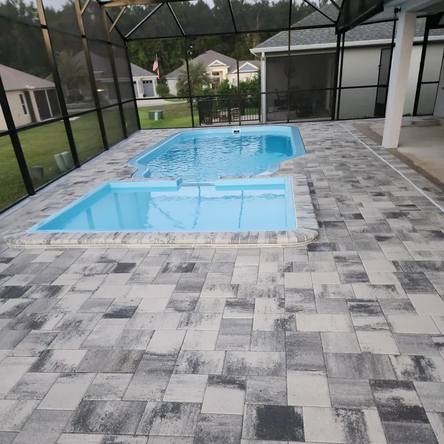 Fiberglass pool and spa under a screen enclosure with a paver deck, built by Homery